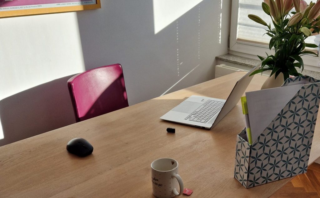 Arbeitsplatz von Madame KI mit Laptop, Schreibtisch und Blumen